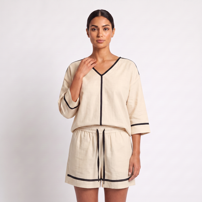 Detail of the top - V-neck with black tape trim, centre-front tape and sleeve cuff bands