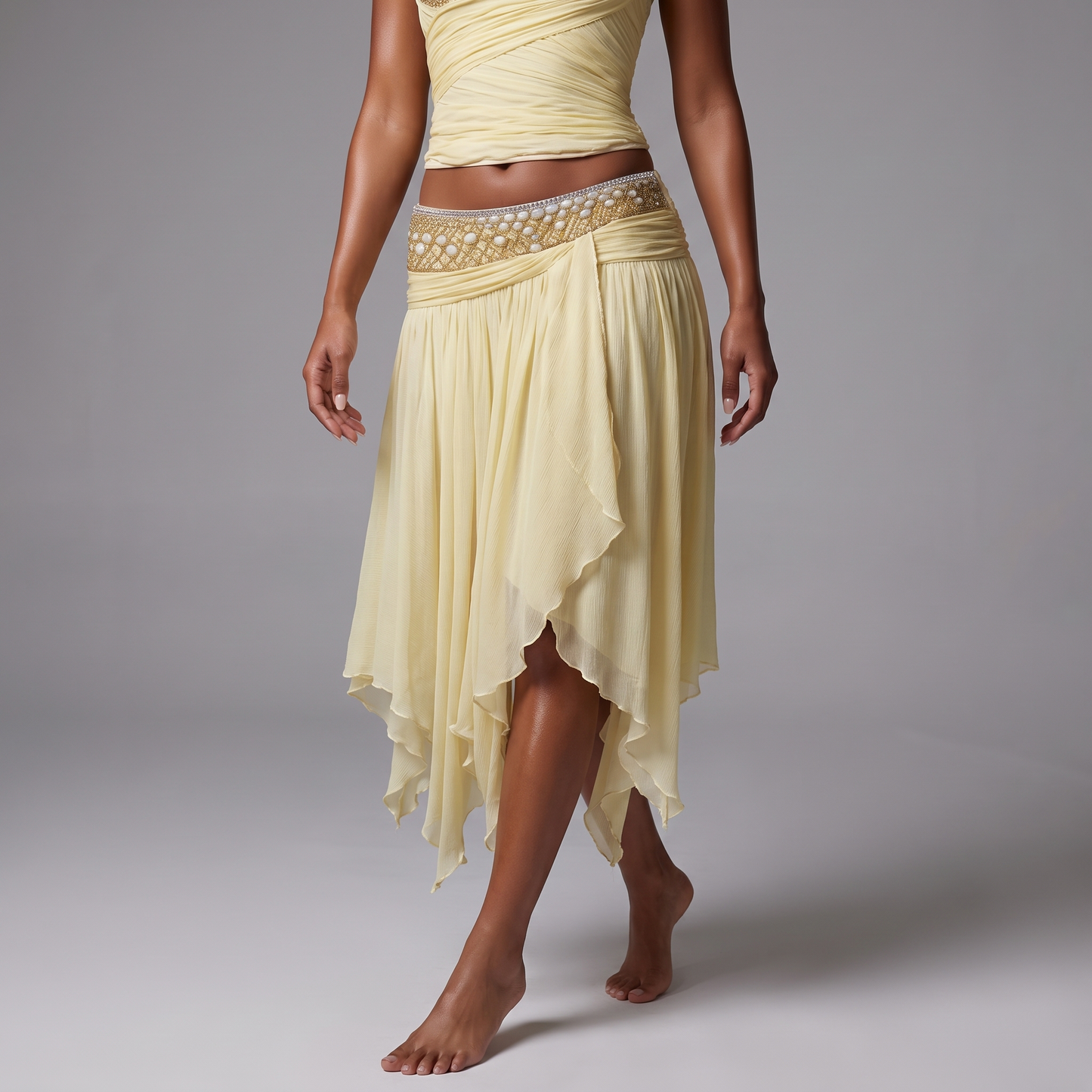 Close detail of the beaded low rise waistband and irregular handkerchief hem of the pale yellow chiffon skirt