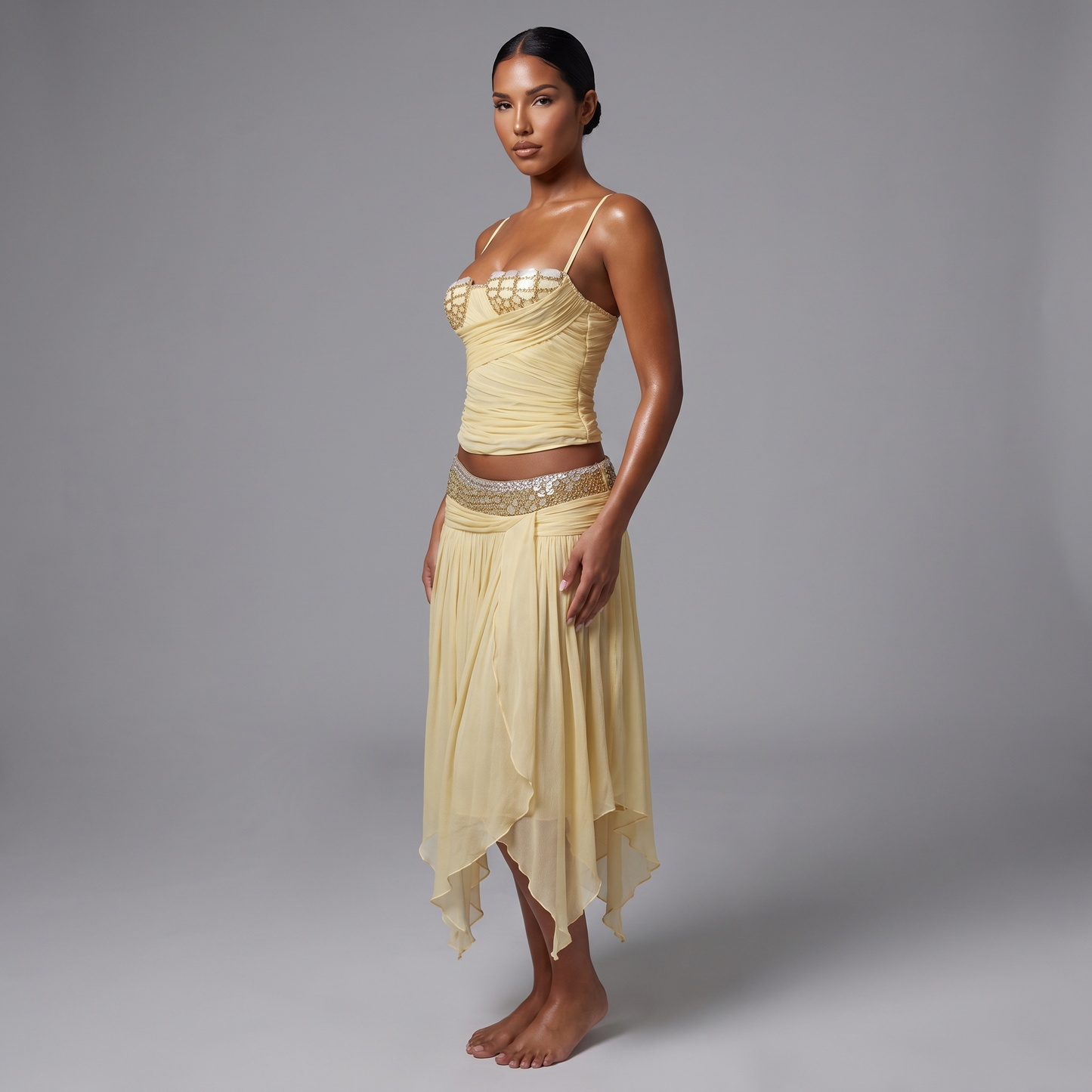 Pale yellow beaded corset top and handkerchief hem midi skirt set, three quarter view on a neutral studio backdrop