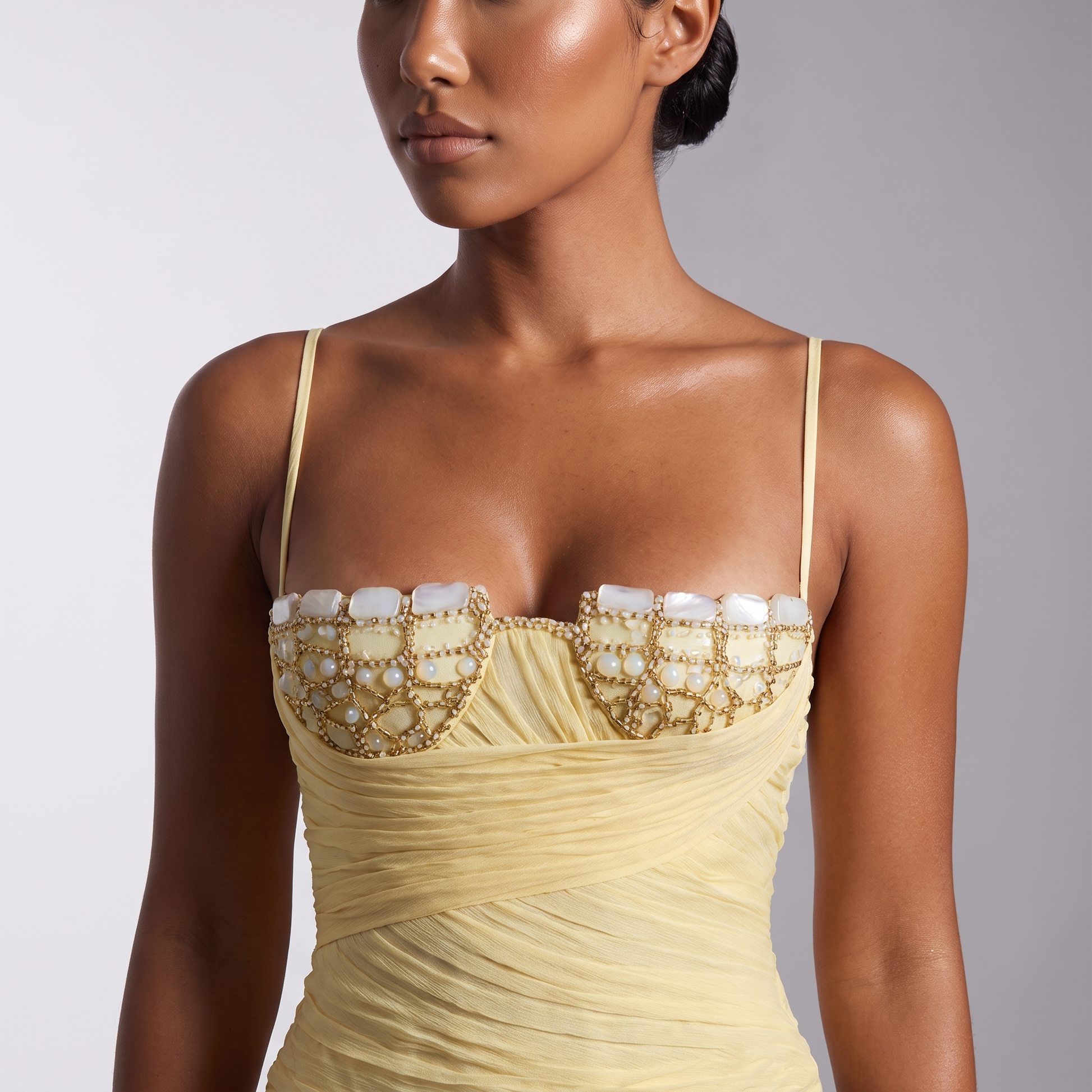 Close detail of the gold beaded trellis and mother of pearl stones on the bust cups of the pale yellow corset top