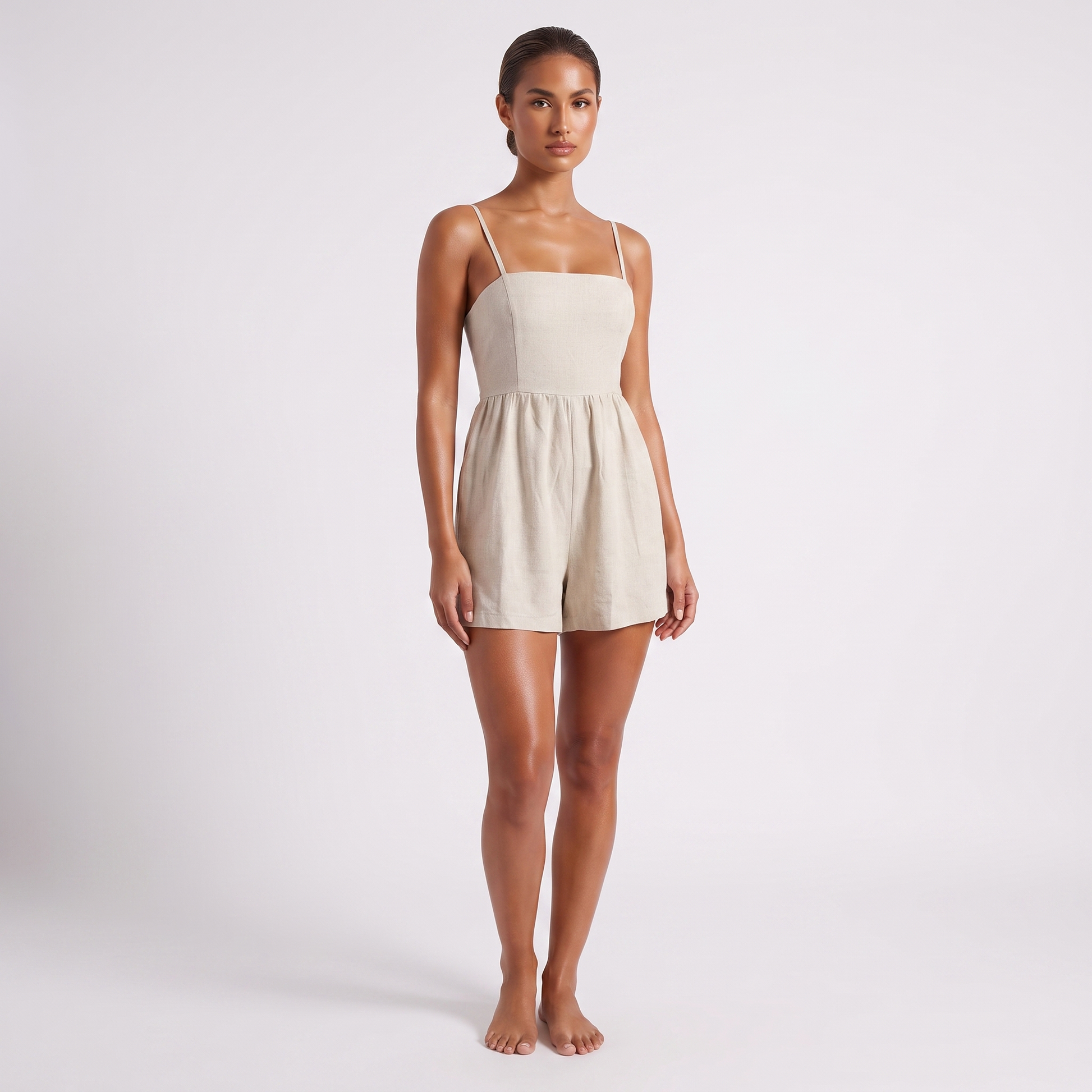 Casual Linen Romper in Apricot oatmeal linen - full length three-quarter view with the front of the garment to camera, showing the bandeau bodice, waist seam and wide gathered shorts hemmed above the knee.